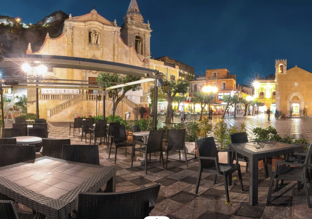 The downtown of Taormina at night with chairs set out at tables