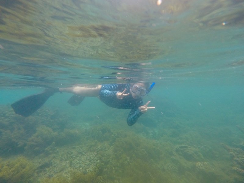 Allison's partner snorkeling in Tahiti and giving two peace signs while underwater above a coral reef