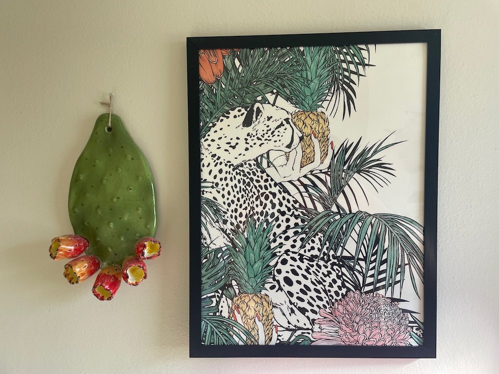 Leopard and Tahitian pineapple print next to another piece of decorative wall art, a ceramic cactus