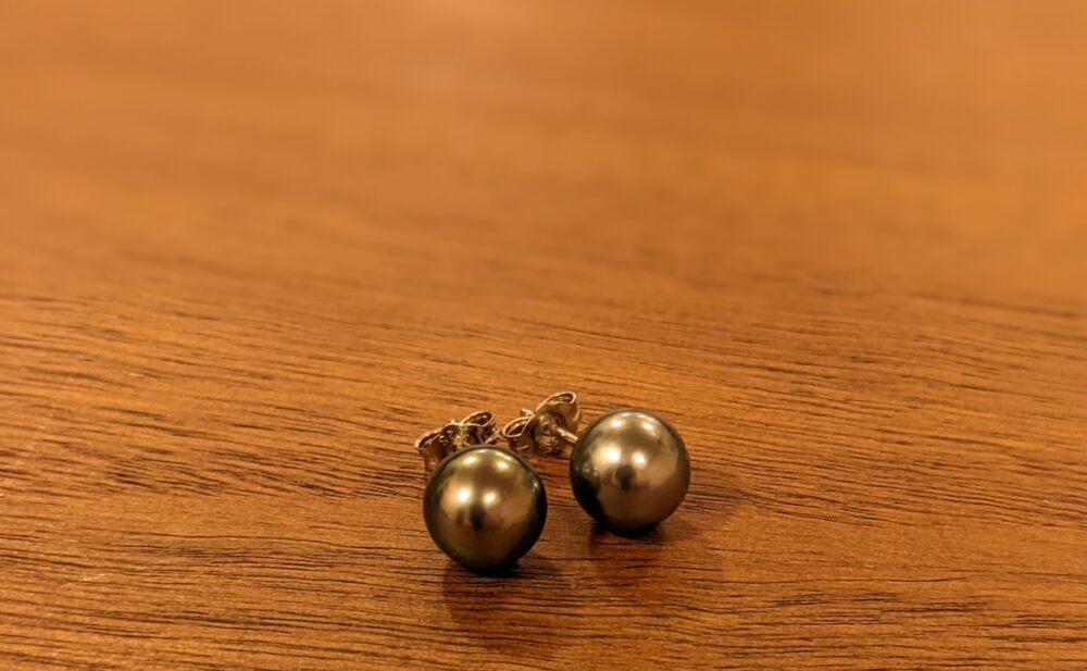 a pair of Tahitian black pearl earring studs on a wooden table