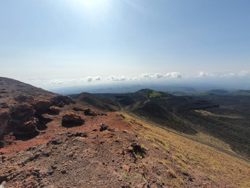 View of Mount Etna while hiking the mountain, reddish brown dirt and skyline and horizon