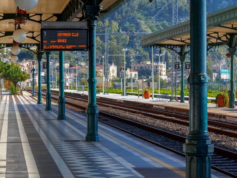 Train station in Taormina, Sicily with a track showing a train departing for Catania at 9:03 