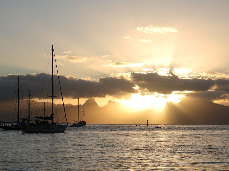 View of Moorea with the sun setting behind it while out on the water in Tahiti