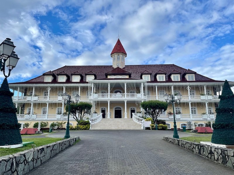 The town hall in Papeete with two stories, yellow and red colors, with Christmas lights strung up and the word "family" in French written in lights in the front