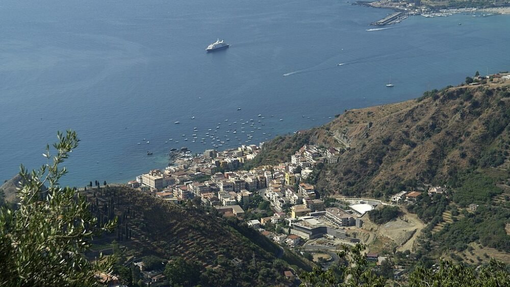 View of Villagonia from up above, looking down onto the marina with boats and beach coastline below.