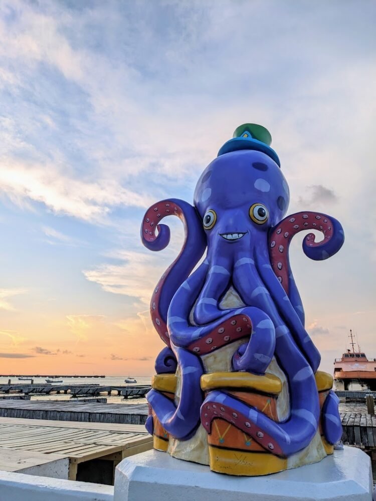 A tacky purple octopus sculpture on the boardwalk in Cozumel at sunset