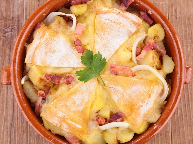 A portion of tartiflette, a dish with potatoes, cheese, cured meat and onion 