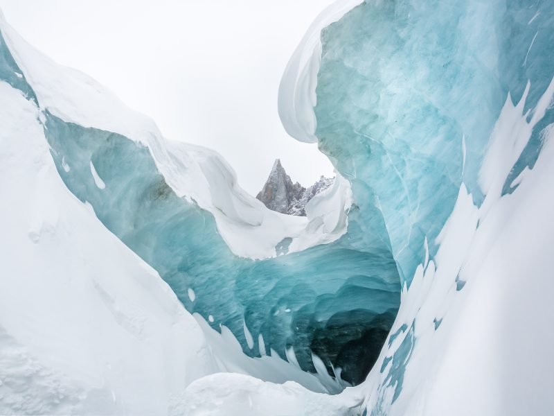 Ice cave with blue tones and white snow in Chamonix in winter