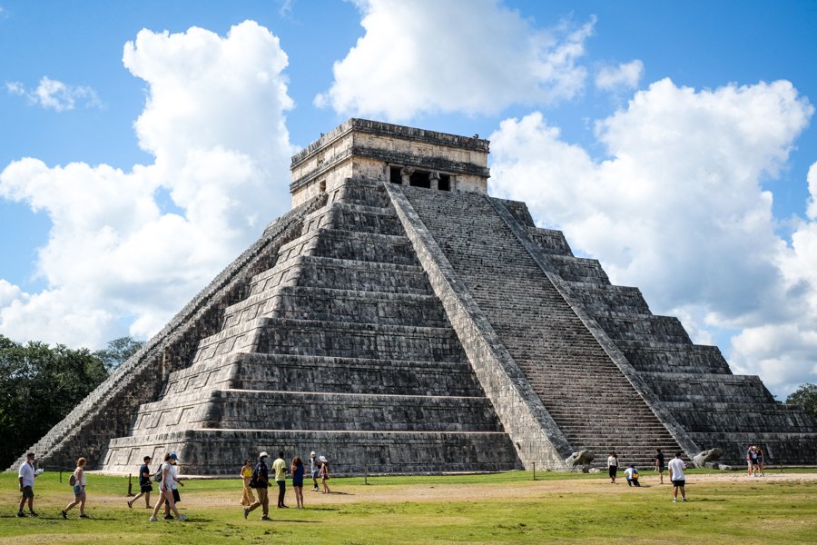 view of the large pyramid of chichen itza with people walking around the base of the pyramid