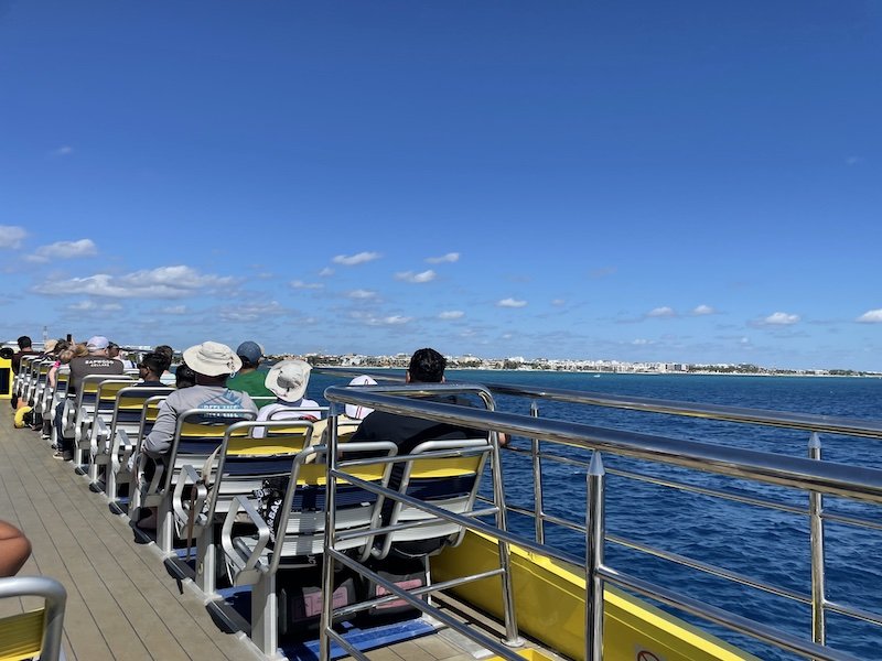 People sitting on the top deck of the UltraMar ferry nearing Playa del Carmen on a sunny day