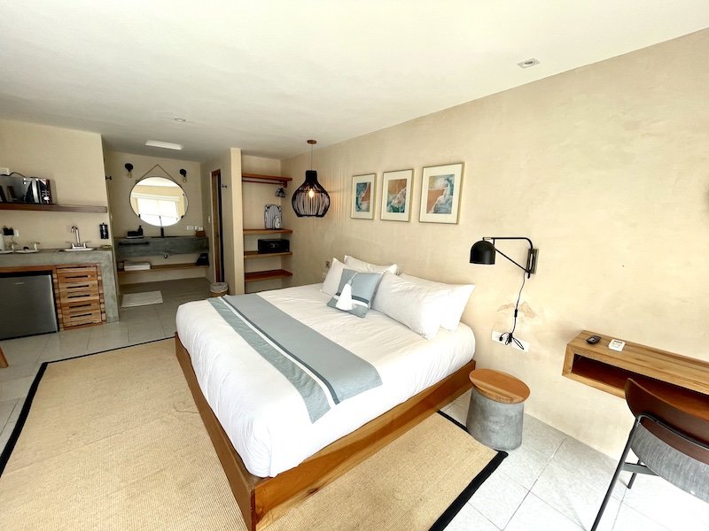 Boutique hotel room with sand-colored walls, beachy elements, small kitchenette and large mirror and bathroom area