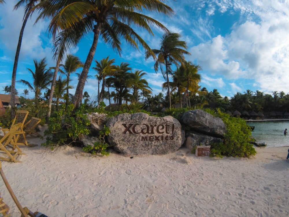 View of Xcaret park with a photo of the sign and water and palm trees