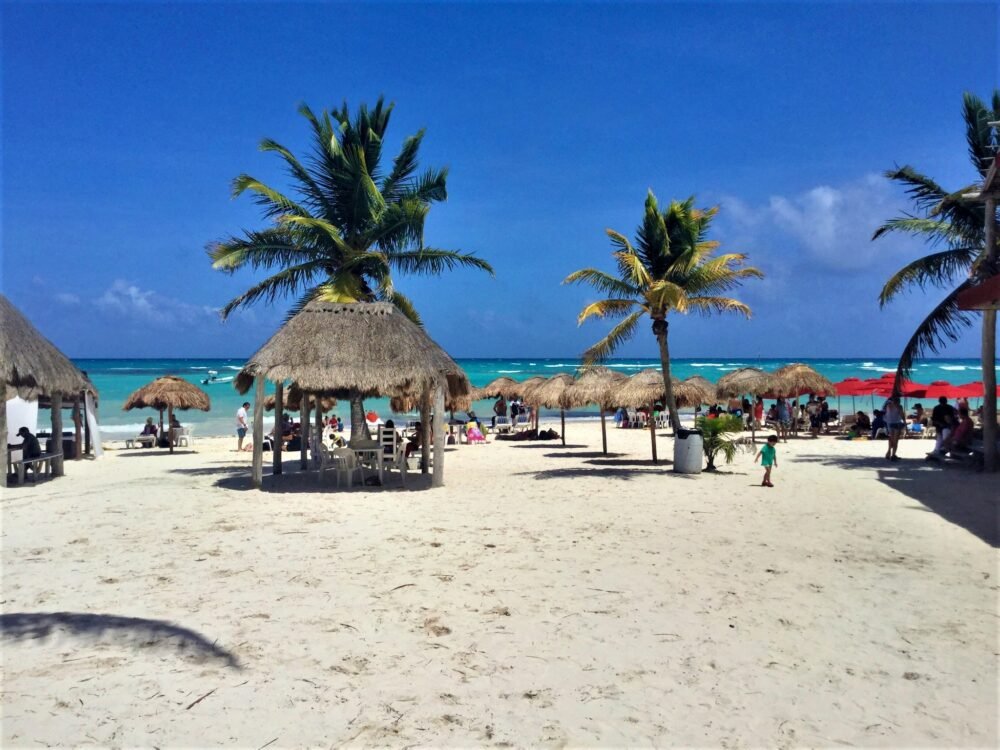 Sandy beach at Xpu-Ha with people on the beach and lots of beach umbrellas