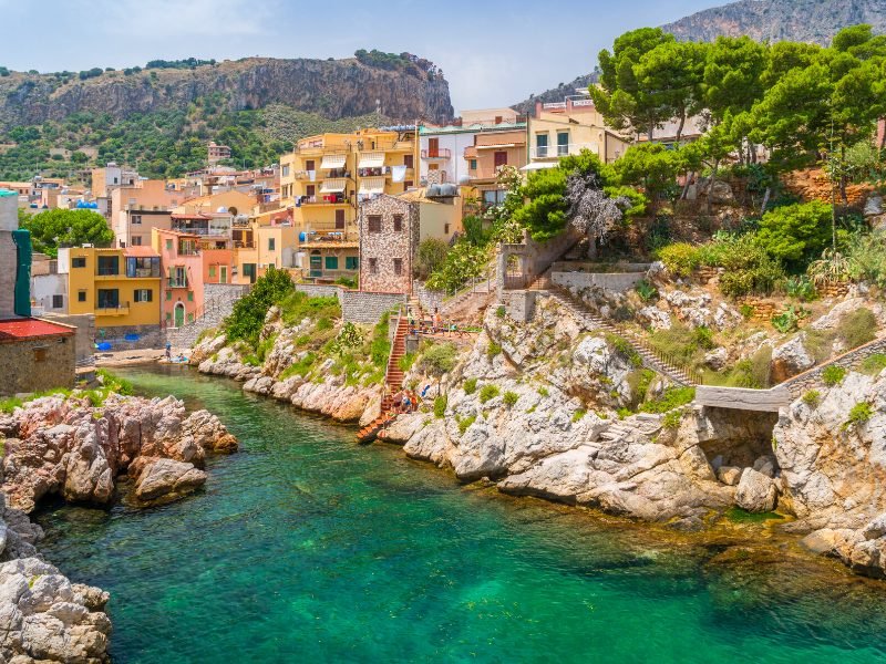 Turquoise sea water, houses on the shores, stairs leading down to see in a small narrow but beautiful cove