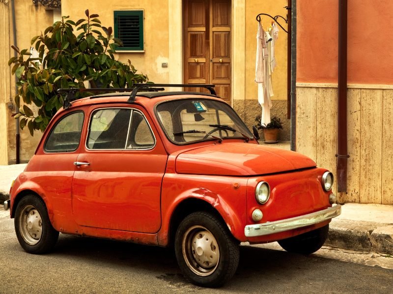 A charming red vintage car in Sicily, Italy: renting a car in Sicily is a great idea if you want to explore more remote beaches near Palermo!