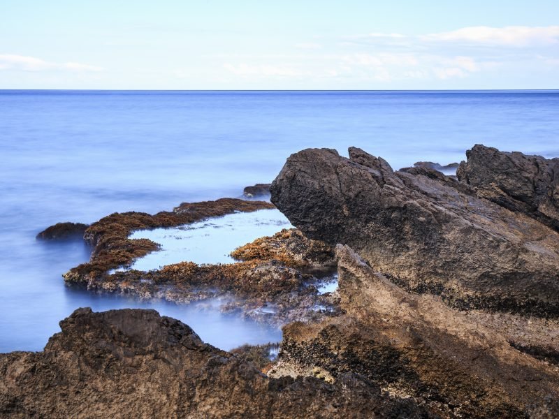 Rock pools with water collecting and sea lapping at the edges of the rocky coastline