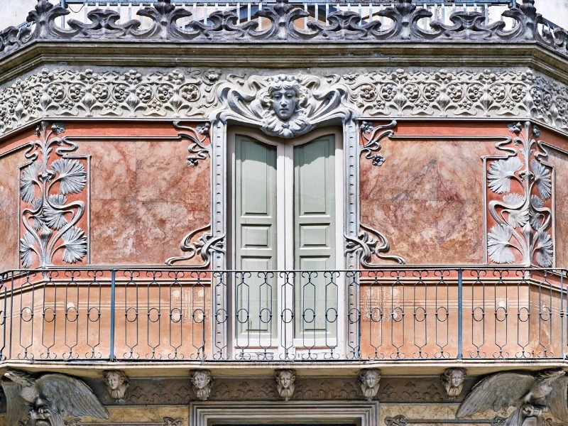 Balcony in Catania with ornate carving, including a face, doors, and balcony