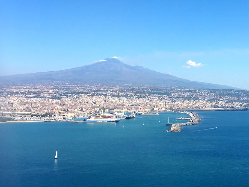 View of Mt Etna in the summer time with no snow on the top, and the city of Catania on the coastline of Sicily