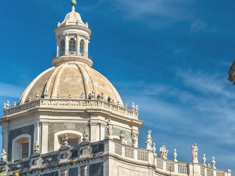 People at the top of the Chiesa della Badia di Sant'Agata, a famous church in Catania that has a beautiful panoramic viewpoint, on a sunny day with just a few clouds