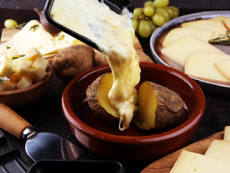 Raclette being served in a French restaurant with potatoes and cheese