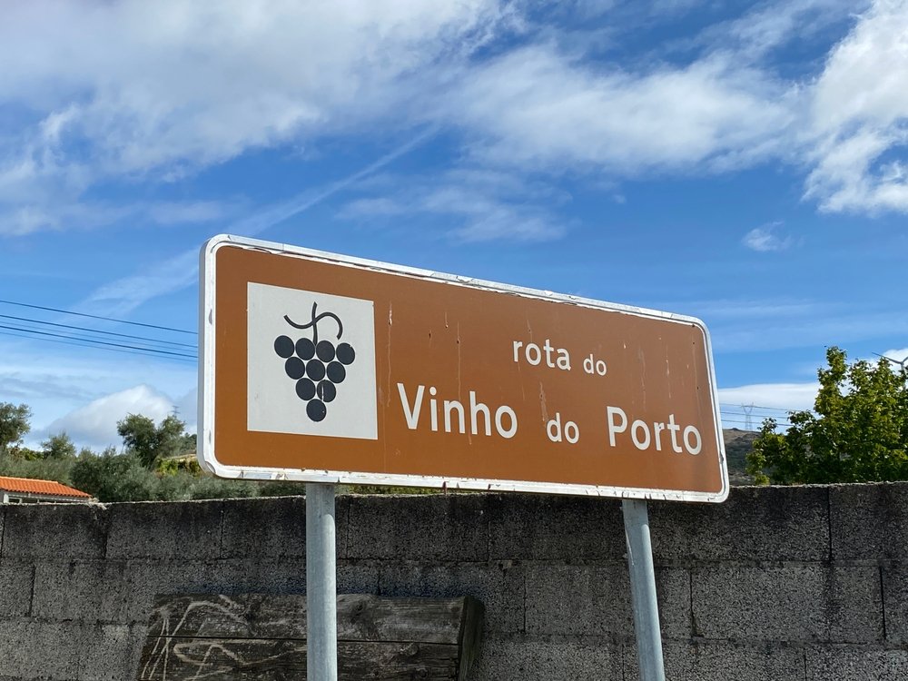 Close up portrait of brown street road for the scenic Douro valley. The sign's translation: Rota do Vinho do Porto - Port Wine Route.