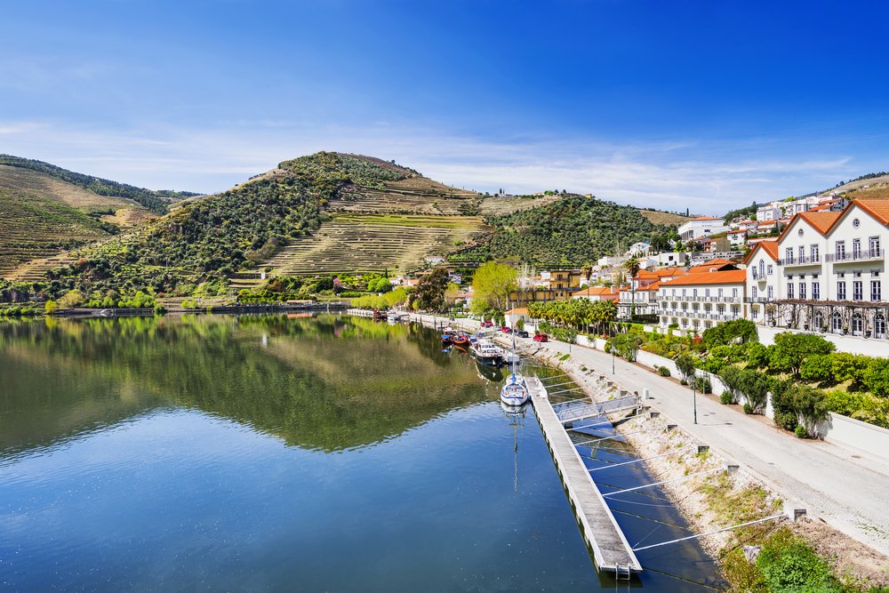 Pinhao town waterfront, with Douro river and vineyards in the beautiful Douro valley, Portugal, with a few boats on the water.