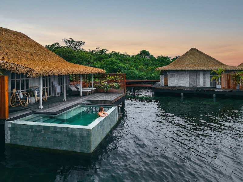 a woman hanging out in the pool area of her luxury accommodations which is an overwater bungalow in panama