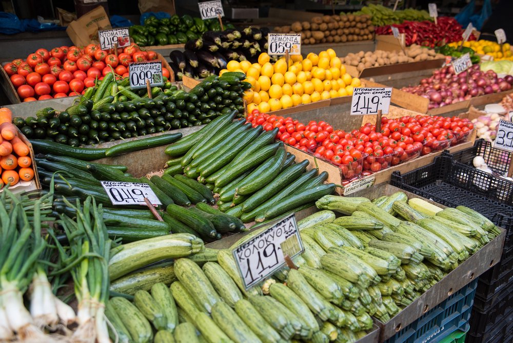 Vegetables like cucumber, squash, tomatoes, lemons, eggplant, red onions at a market in Athens before a cooking class