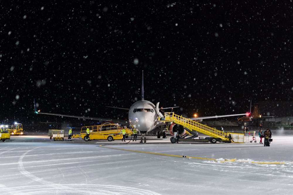 The airport in Kiruna with people loading up the plane even though it is very snowy outside