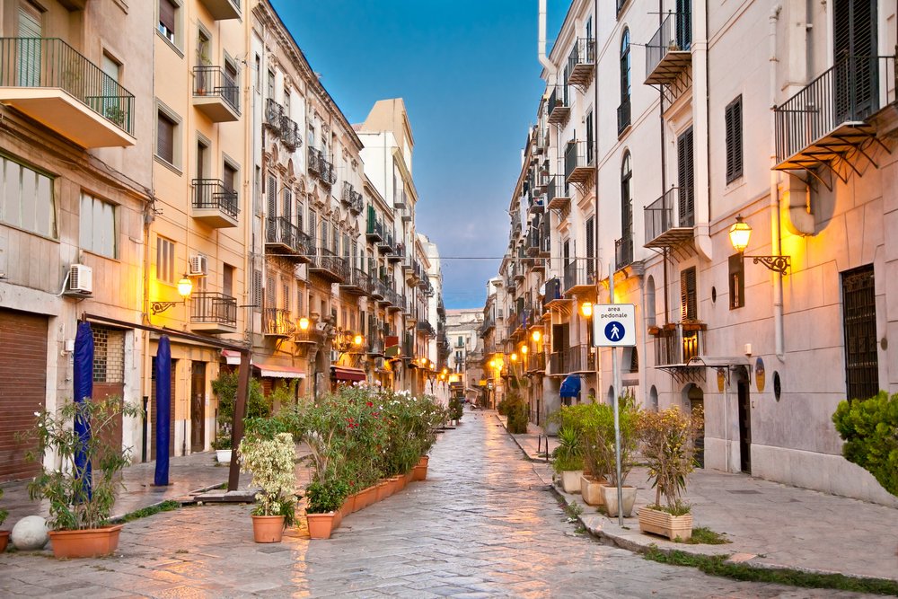 Street in La Kalsa or Mandamento Tribunali, the old Arab quarter of Palermo, with street lights on and pedestrian only street sign