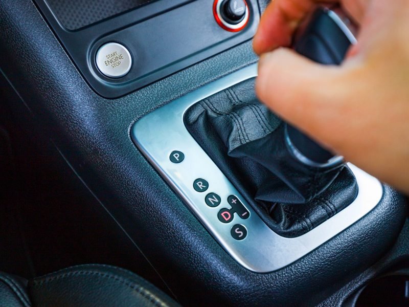 Someone's hand on an automatic transmission car changing gears into drive.