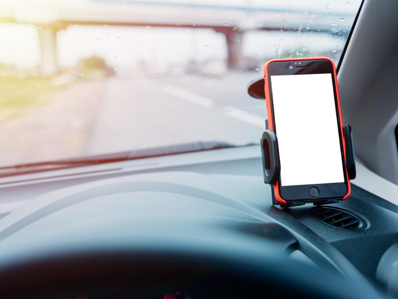 A blank phone in a a cell phone holder in a car, showing the intent to navigate