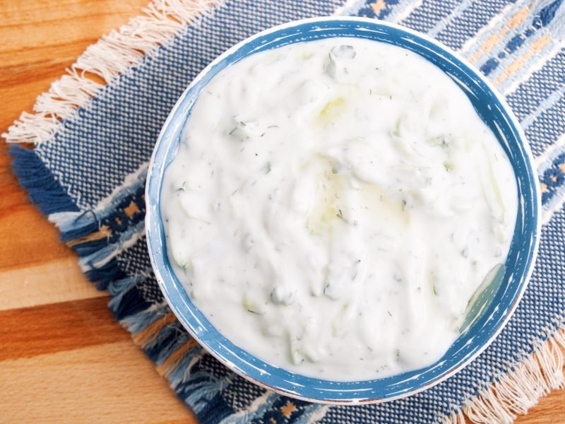 traditional Santorini meze dish of greek yogurt and herbs and cucumber called tzatziki served in a bowl on a towel