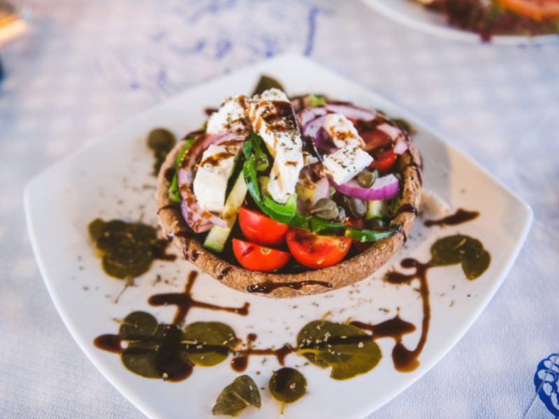 A traditional Santorini salad with goat cheese, cucumber, red onion, dressing, and tomatoes