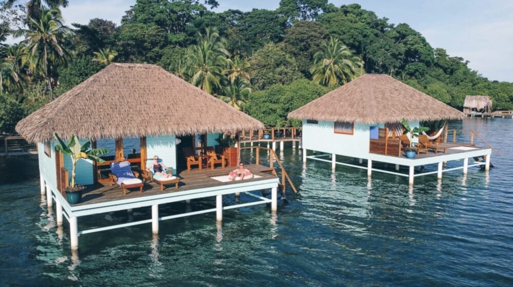 Two bungalows with hammock, net, deck chairs, perched over the water in Bocas del Toro with forest in the background