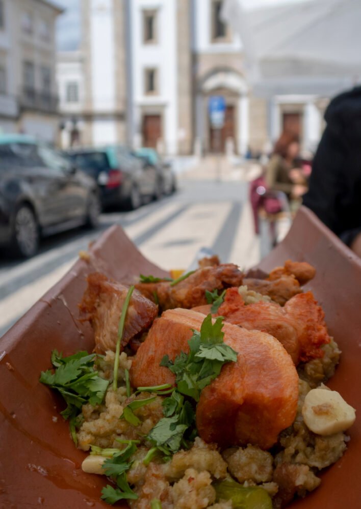 Alentejo food on a ceramic tile plate in front of a church