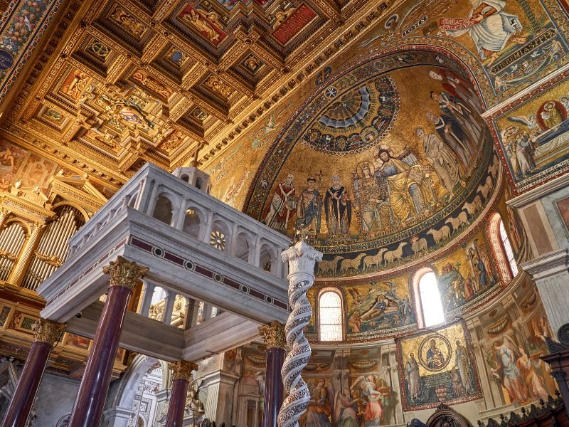 The famous golden and mosaic interior of the Basilica of Our Lady in Trastevere with many ornate detail work on the dome and organ and walls