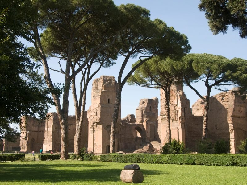 Stones standing in a park with many trees, the remnants of a historic Roman public bath establishment