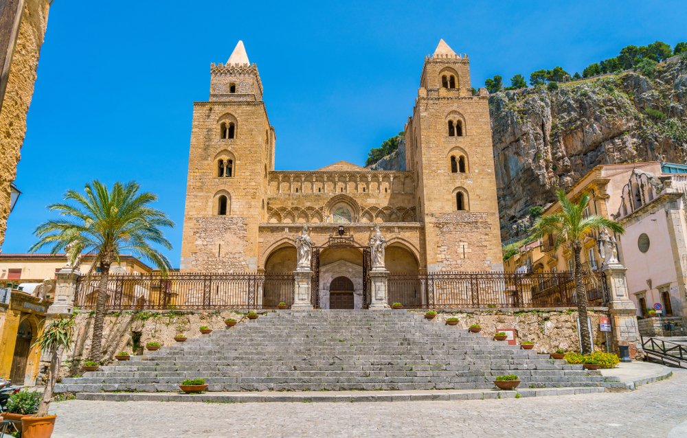 Steps leading up to the Cefalu Cathedral, an Arab-Normal church part of the UNESCO site, near Palermo, with mountains behind the church.