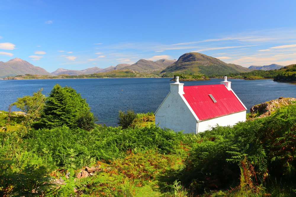 Small Red and White Cottage overlooking Loch Sheildaig with the Torridon Mountains in the distance