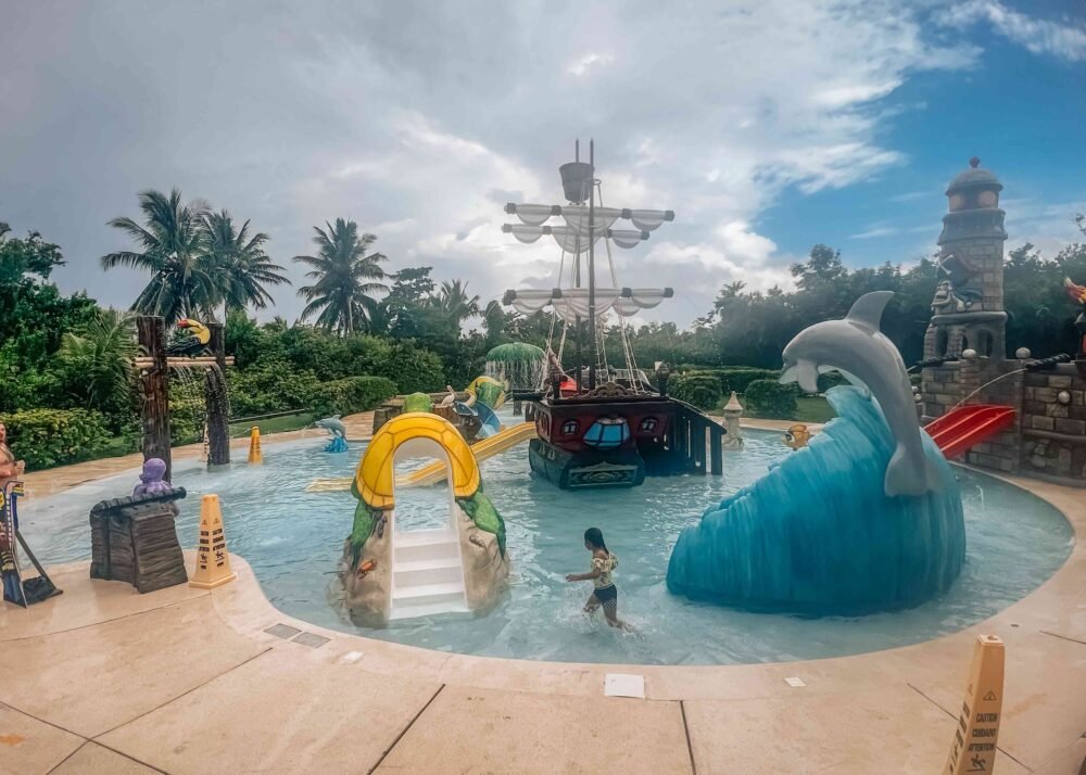 Dolphin, pirate ship, etc. in a pool on an overcast day with kids enjoying the water in Cozumel at a water park