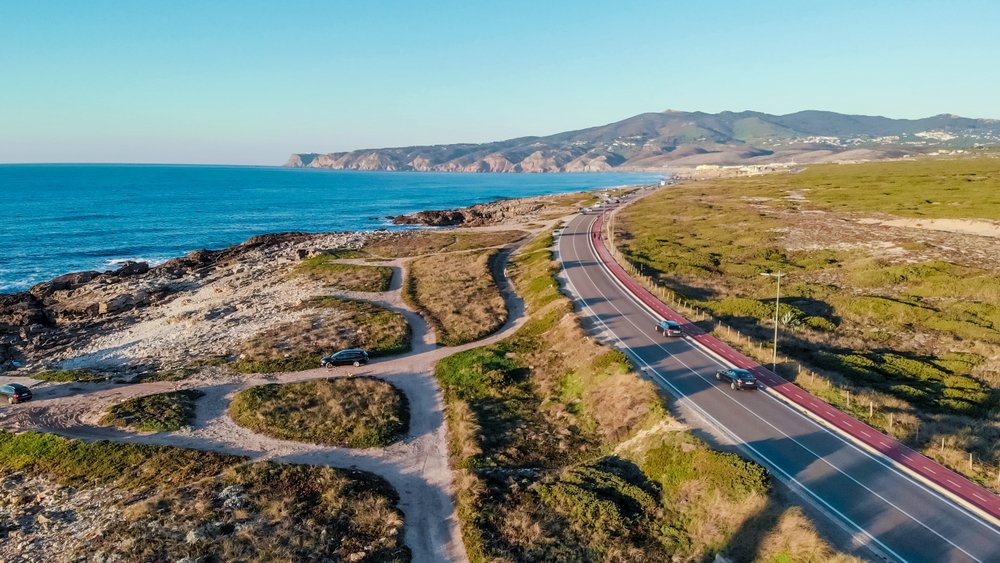 Aerial view of the road from above, ocean on one side, cars driving on a highway