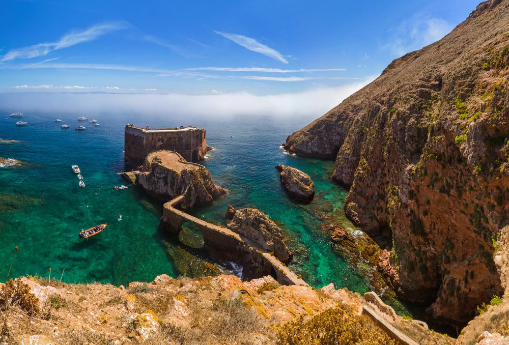 Fort in Berlenga island in Portugal with teal and dark blue ocean waters and mist on the horizon