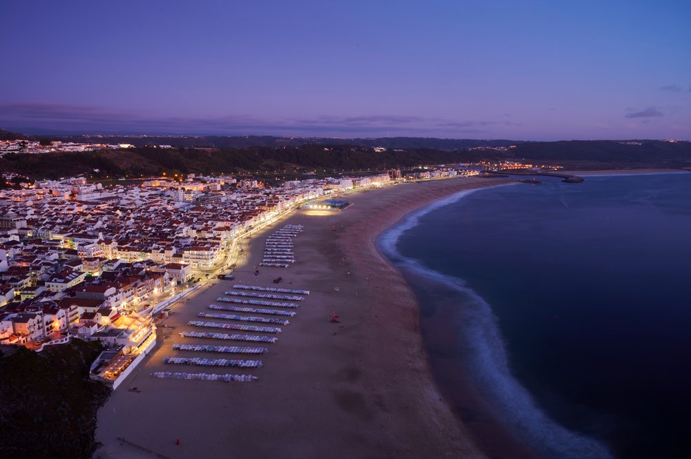 View at the end of the day over the town and beach of Nazaré with lights on over the city and the beach looking peaceful and quiet