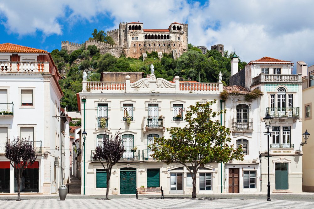 the beautiful town of leiria with a medieval castle at the top of the hill and white architecture on the ground level