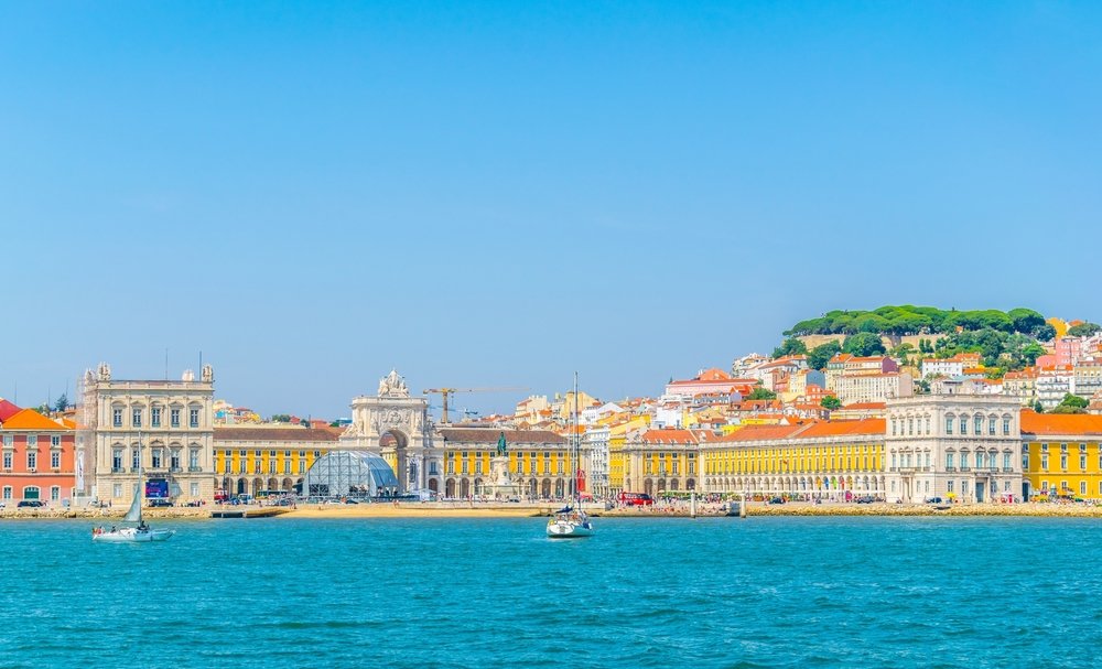 View of central Lisbon from the River looking onto the city's yellow toned buildings and hills covered in buildings and trees