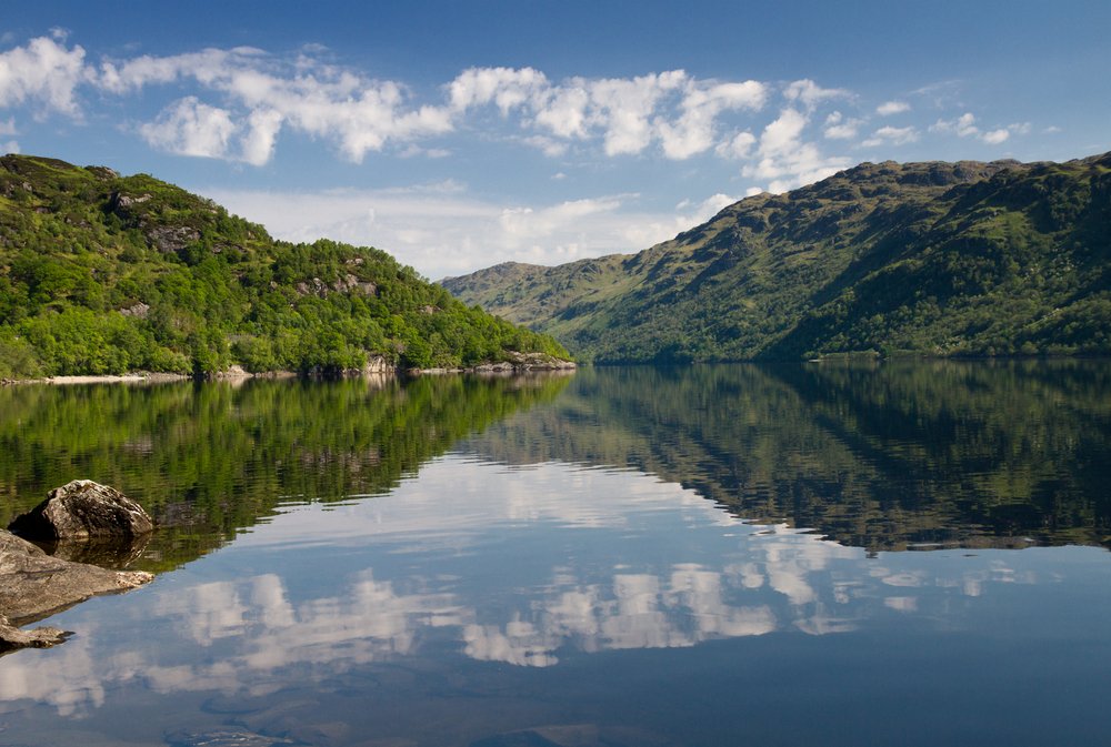 Reflections of trees and clouds on Loch Lomond, Scotland