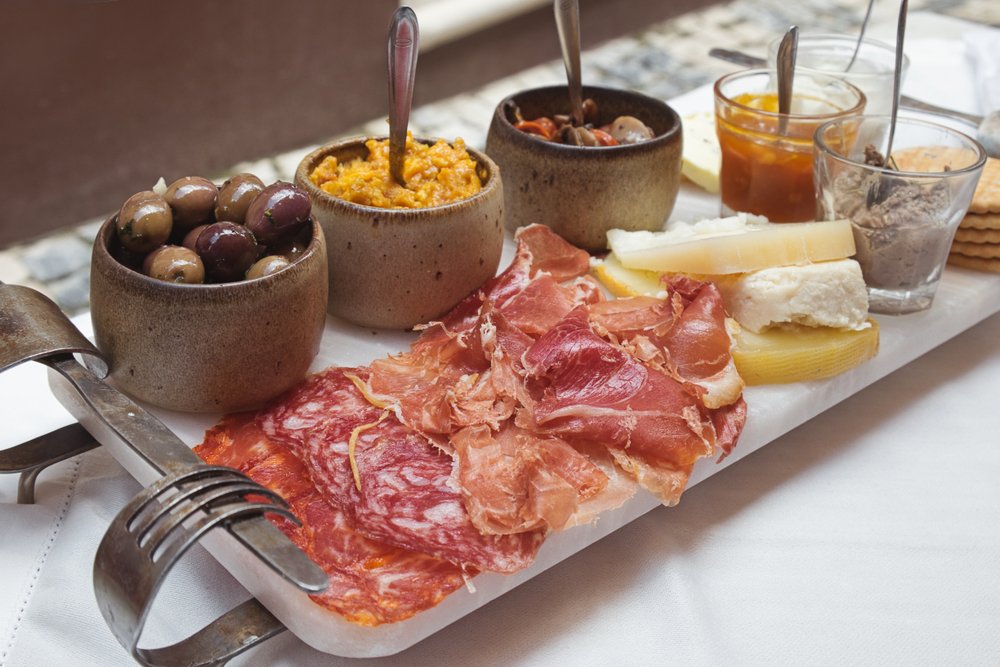 A selection of best portuguese tapas - smoked ham, salami, chorizo sausages, a variety of cheese, crackers, liver pate and several traditional jams