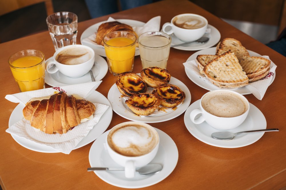 breakfast in portugal with croissant, orange juice, cappuccino, pressed sandwiches