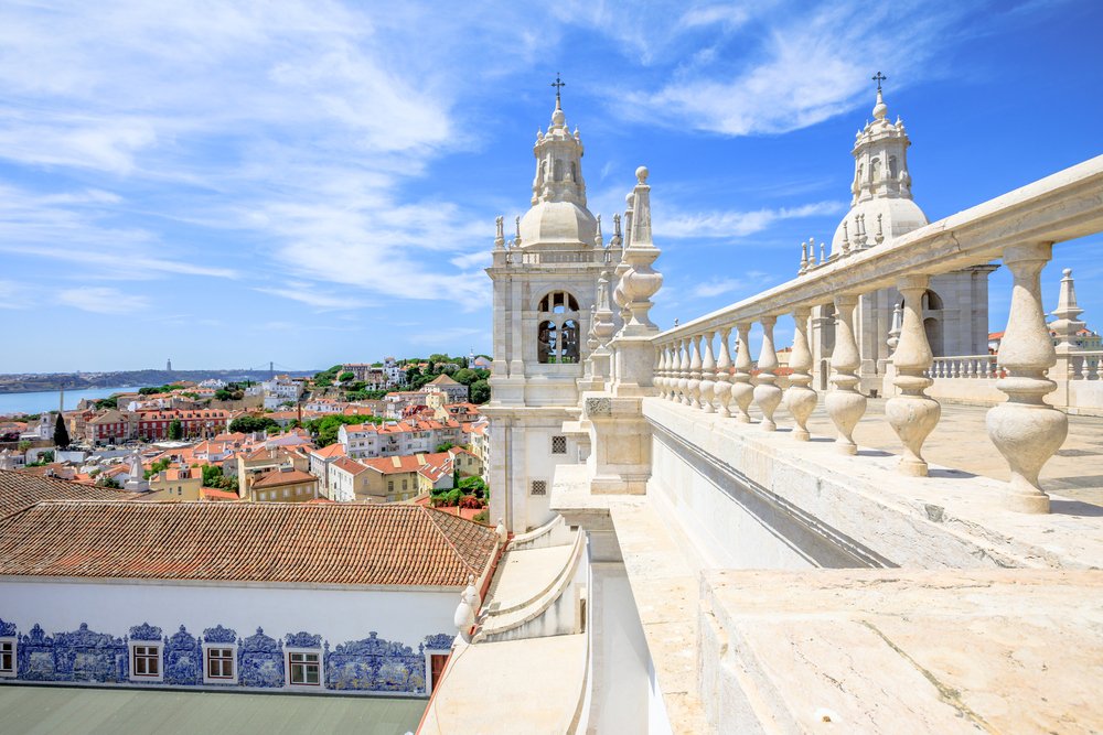 Spectacular view of 25 April Bridge, Tagus River and colorful Alfama neighborhood from roof top of popular Church of Sao Vicente of Fora